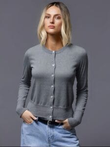 A young woman stands confidently against a gray background, her gaze directed towards the camera with an air of.