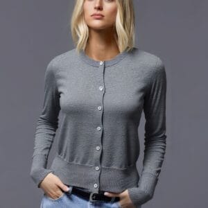 A young woman stands confidently against a gray background, her gaze directed towards the camera with an air of.