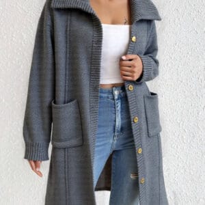 A person is standing against a white wall with their hands in their pockets.