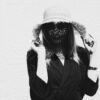 COCOLOGO sustainable fashion portrait of woman wearing dark collared jacket and wide-brimmed straw hat, eco-friendly knitwear