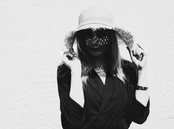 COCOLOGO sustainable fashion portrait of woman wearing dark collared jacket and wide-brimmed straw hat, eco-friendly knitwear