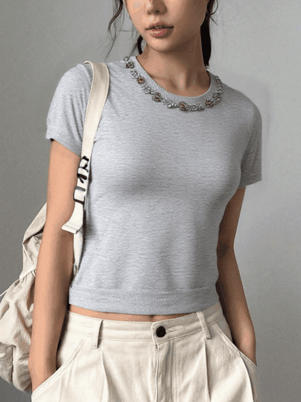 There is a young woman standing against a plain gray background.