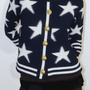 A person stands against a white background, wearing a navy blue sweater with white stars and gold buttons cinched at the.