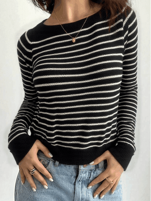 A person stands against a white wall with their hands casually tucked into their pockets and fingers spread apart.