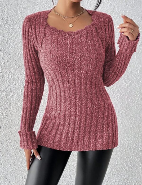 A woman stands confidently against a white wall, wearing a vibrant red sweater with a unique ribbed texture and a necklace.