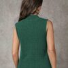 A woman standing against a gray background, wearing a vibrant green sleeveless top with a ribbed texture and.