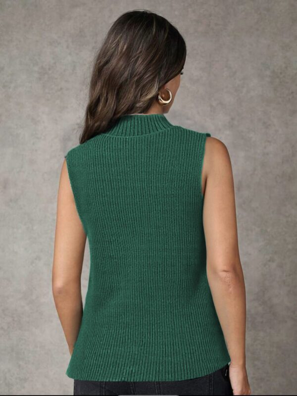 A woman standing against a gray background, wearing a vibrant green sleeveless top with a ribbed texture and.