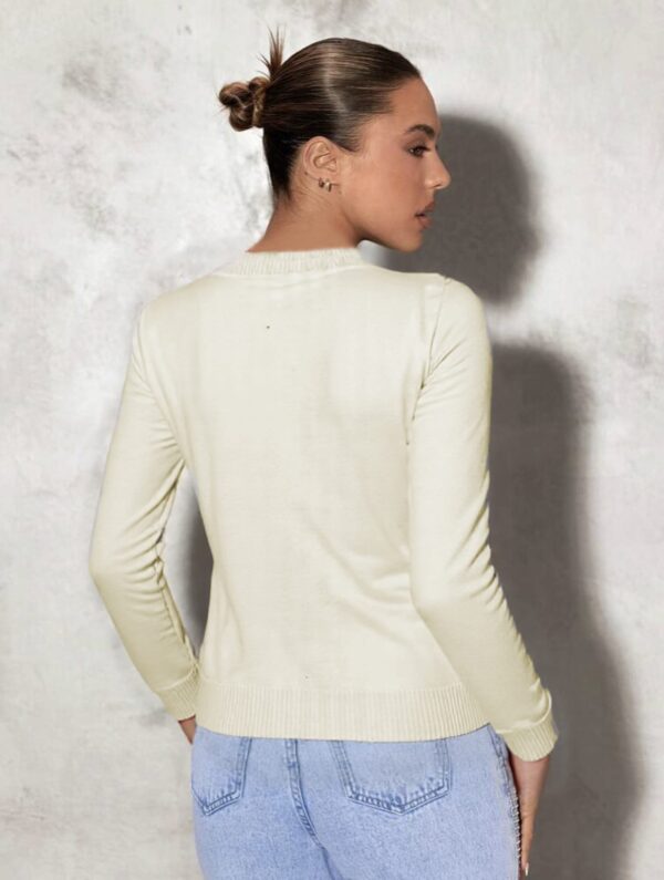 A woman standing against a gray wall.